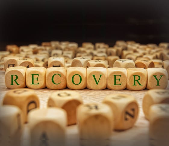 Wooden blocks spelling "RECOVERY" with scattered blocks in the background.